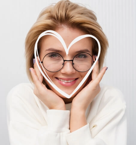 Smiling woman wearing black Selen Eyewear glasses with a white heart outline